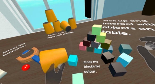 VR tabletop scene with colorful blocks to stack by color; on-screen instructions read 'Stack the blocks by colour' and 'Pick up and interact with objects on the table'